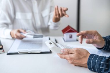 Emlak komisyoncusu analizi yapıyor ve müşteriye emlak kredisi vermeye karar veriyor. Ajan Man detaylar için hesap makinesi kullanıyor ve cevabını bekliyor..