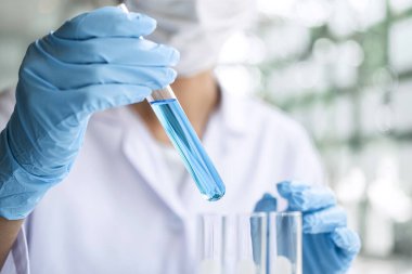 Laboratuvar önlüğündeki bilim adamı ya da tıp laboratuvar önlüğündeki deney tüpünde reaktör, kimyasal sıvı, mikroskop, biyokimya laboratuvarı araştırması içeren laboratuvar camları..
