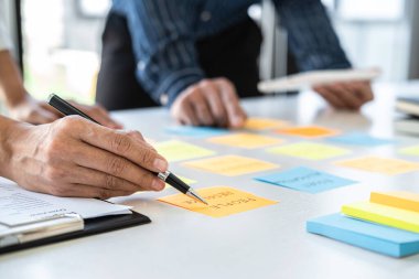 Buluşan ve planlayan iki yaratıcı iş adamı, fikir, analiz veri grafiği ve çalışma stratejisi ile ofis içinde beyin fırtınası yapmak için masaya yapışkan notlar bırakırlar..