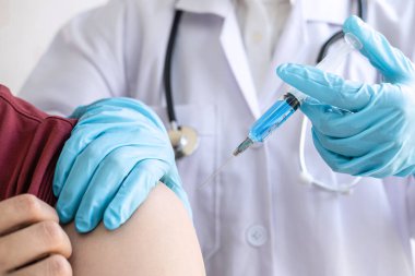 Klinikte salgını, gribi ya da grip virüsünü önlemek için aşı yapan doktor.