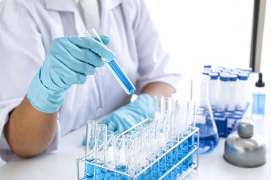 Biyoteknoloji laboratuarında çalışan bilim adamı ya da tıp klinik laboratuarında cam şişedeki reaksiyonlarla araştırma için ekipman kullanılıyor..