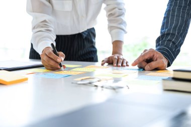 Buluşan ve planlayan iki yaratıcı iş adamı, fikir, analiz veri grafiği ve çalışma stratejisi ile ofis içinde beyin fırtınası yapmak için masaya yapışkan notlar bırakırlar..