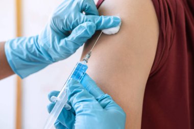 Klinikte salgını, gribi ya da grip virüsünü önlemek için aşı yapan doktor.