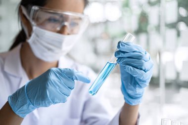 Laboratuvar önlüğündeki bilim adamı ya da tıp laboratuvar önlüğündeki deney tüpünde reaktör, kimyasal sıvı, mikroskop, biyokimya laboratuvarı araştırması içeren laboratuvar camları..