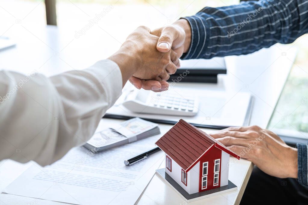 Real estate agent and customers shaking hands together celebrating finished contract after signing about home insurance and investment loan, handshake and successful deal.