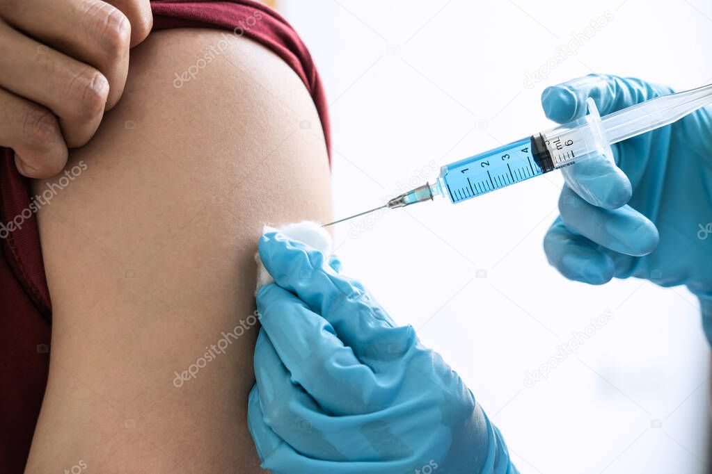 Doctor making injection vaccination patient to prevent pandemic of the disease, flu or influenza virus in clinic.