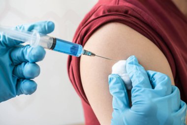 Klinikte salgını, gribi ya da grip virüsünü önlemek için aşı yapan doktor.
