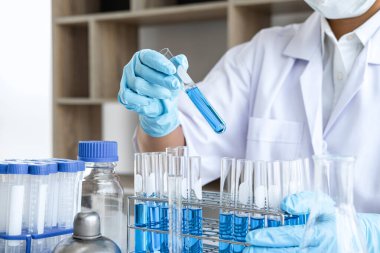 Biyoteknoloji laboratuarında çalışan bilim adamı ya da tıp klinik laboratuarında cam şişedeki reaksiyonlarla araştırma için ekipman kullanılıyor..