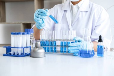 Biyokimya laboratuvarı araştırması. Kimyager laboratuvarda kimyasal sıvı içeren ekipman ve bilimsel deneylerle numune analiz ediyor..