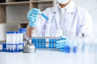 Biyoteknoloji laboratuarında çalışan bilim adamı ya da tıp klinik laboratuarında cam şişedeki reaksiyonlarla araştırma için ekipman kullanılıyor..
