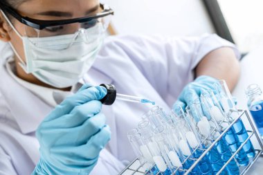 Biyokimya laboratuvarı araştırması. Kimyager laboratuvarda kimyasal sıvı içeren ekipman ve bilimsel deneylerle numune analiz ediyor..