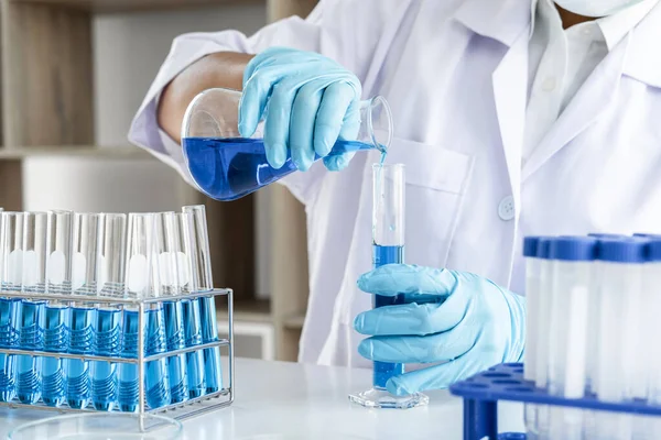 研究室で働くガラス装置に色液を滴下させた試薬を用いて試験管を保持する実験室の化学研究室 科学者又は医学 — ストック写真