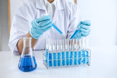 Biyoteknoloji laboratuarında çalışan bilim adamı ya da tıp klinik laboratuarında cam şişedeki reaksiyonlarla araştırma için ekipman kullanılıyor..