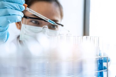 Biyokimya laboratuvarı araştırması. Kimyager laboratuvarda kimyasal sıvı içeren ekipman ve bilimsel deneylerle numune analiz ediyor..