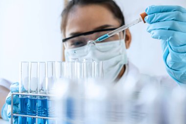 Biyokimya laboratuvarı araştırması. Kimyager laboratuvarda kimyasal sıvı içeren ekipman ve bilimsel deneylerle numune analiz ediyor..