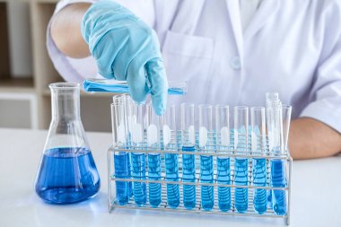 Biyoteknoloji laboratuarında çalışan bilim adamı ya da tıp klinik laboratuarında cam şişedeki reaksiyonlarla araştırma için ekipman kullanılıyor..