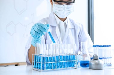 Biyokimya laboratuvarı araştırması. Kimyager laboratuvarda kimyasal sıvı içeren ekipman ve bilimsel deneylerle numune analiz ediyor..