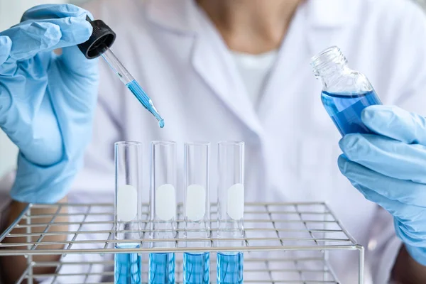 Laboratuvarda çalışan cam teçhizatı üzerine bir damla renk sıvısı ile mikroskop reaktörü kullanarak laboratuvar önlüğü içinde bilim adamı ya da tıbbi araştırma..