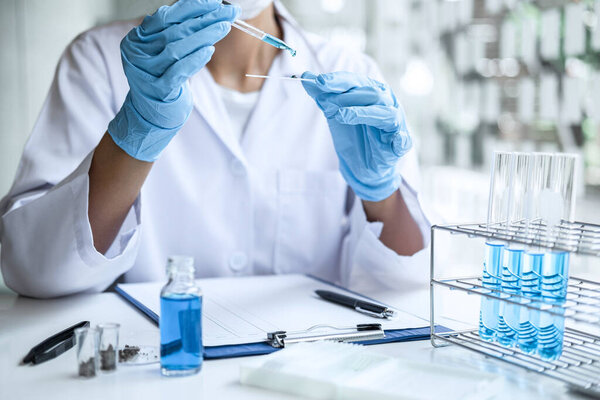 Scientist or medical in lab coat holding test tube with reagent, mixing reagents in glass flask, glassware containing chemical liquid, laboratory research and testing of Microscope.