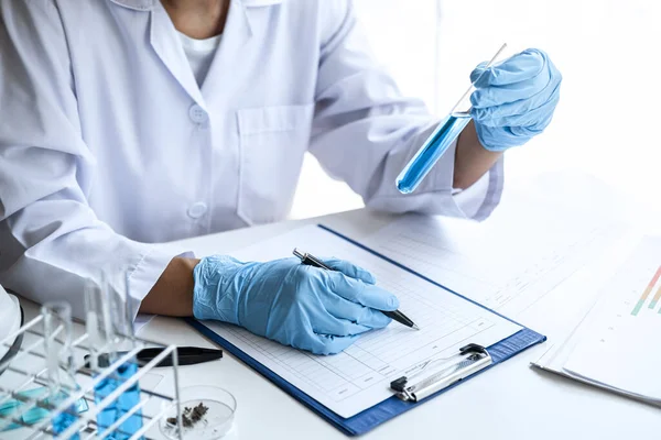 試薬付き試験管を有する研究室のコートの科学者又は医療 化学液体を含む研究室のガラス製品 顕微鏡 生化学実験室の研究 — ストック写真