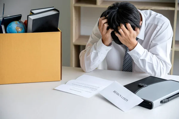 Images of packing up all his personal belongings and files into a brown cardboard box, Businessman has frustrated and stressed to resignation and signing cancellation contract letter in office.