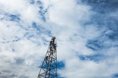 İnşaat işçisi inşaat alanında merdivenle çalışıyor ve güzel bir bulut, gökyüzü arkaplanı..