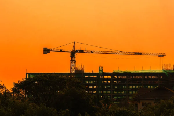 Silhouette tower crane and building on site Industrial construction on sunset background.