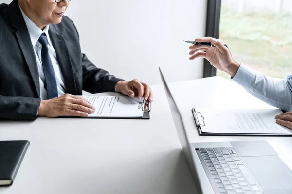 Senior committee manager reading a resume during a job interview, Employer interviewing to ask young male job seeker for recruitment talking in office.