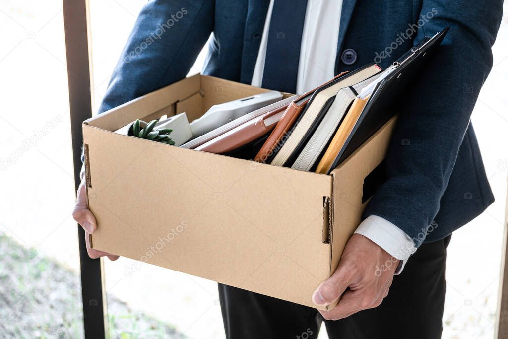 Images of businessman carrying packing up all his personal belongings and files into a brown cardboard box has frustrated and stressed to resignation and signing cancellation contract letter.