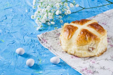 Geleneksel Paskalya hot cross buns peçete ve gökyüzü mavi zemin üzerine. Çiçekli geleneksel ekmek.