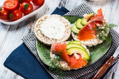 Tuzlanmış somon fileto, çıtır ekmek ve avokado. Aromatik otlar, baharatlar ve sebzeler - sağlıklı yiyecekler, diyet konsepti. Çeri domates. Süper yemek, açık sandviç, açık büfe. kahvaltı kavramı