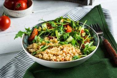 Bir tabak taze salata roka, bulgur, vişneli domates ve mikroyeşille süslenmiş avokado. Fotokopi alanı ile yatay fotoğraf, üst görünüm. Sağlıklı gıda konsepti. diyet yemeği. vejetaryen gıda konsepti.
