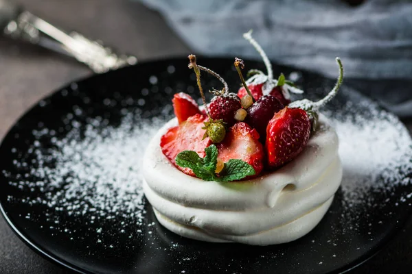 Meringue dessert Pavlova cake with fresh berries on plate. Summer dessert. French cake. Confectionery. Classic dessert. Strawberry dessert