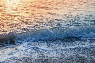 Deniz yüzeyinde, dalga ve günbatımı ışığı