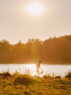 Küçük çocuk nehir kenarında yaz akşam çalışır.