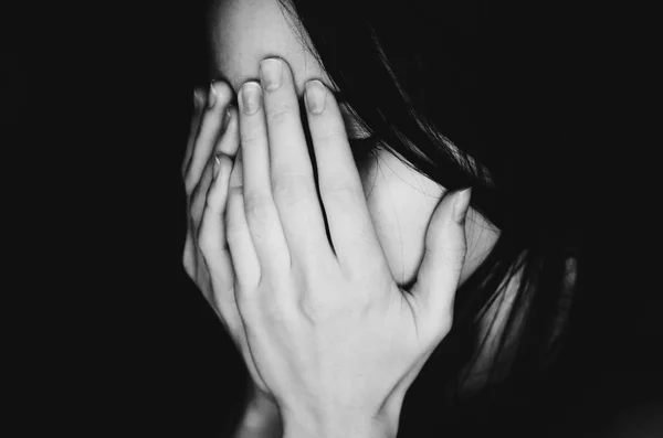 Плаче молода дівчина вкриває обличчя руками чорно-білим — стокове фото
