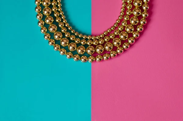 Golden beads on pink blue background — Stock Photo, Image