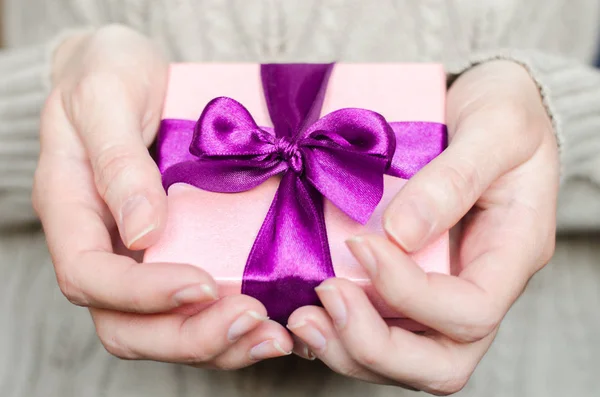 Giovane donna tiene una scatola regalo con un fiocco da vicino — Foto Stock
