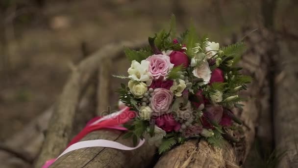 Hochzeitsstrauß aus Rosen und Pfingstrosen zwischen Baumstämmen aus nächster Nähe. der Brautstrauß — Stockvideo