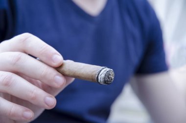 Bir sigara ve holding puro ile arka plan bulanık el yakından görmek