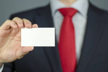 Bir yöneticinin el ile bir takım elbise ile boş bir beyaz iş oyun kağıdı tutan kırmızı kravat görünümünü yakın çekim