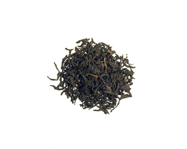 Csendélet egy halom fekete Assam tea levelek szórt az asztalra, elszigetelt fehér background — Stock Fotó
