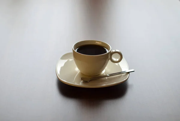 Bodegón con taza de café de porcelana en platillo con cuchara en mesa de madera —  Fotos de Stock
