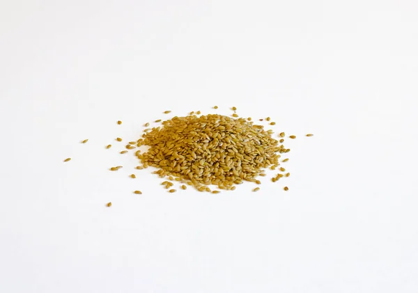 Altın keten tohumu dökülen yığını beyaz bir arka plan üzerinde izole — Stok fotoğraf