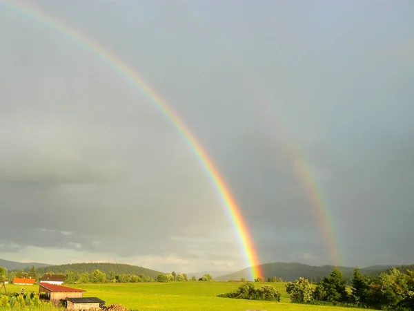 Rainbow pohled na louce se stromy a kopce pod letní modrou oblohou — Stock fotografie