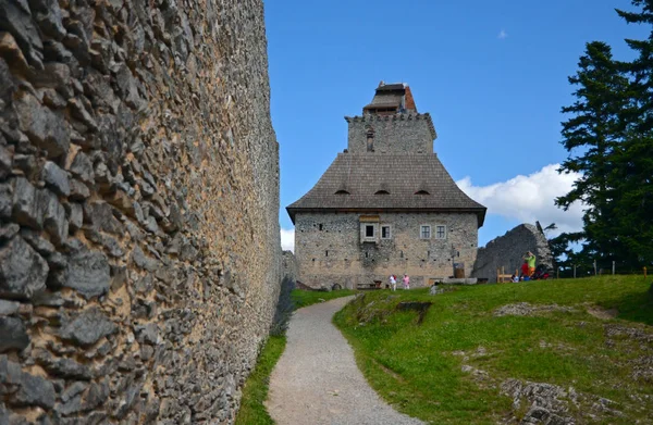 Vista de la gente en el patio de la hierba medieval cubierta de edificios y árboles bajo un cielo azul claro con nubes blancas — Foto de Stock