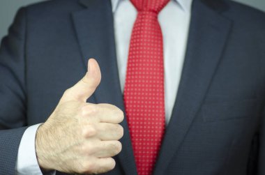 Bir yöneticinin el bir takım elbise ve başparmak ile kırmızı kravat yakından görmek