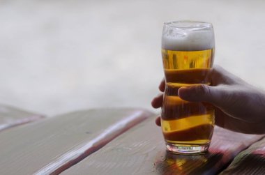 Bir bardak bira bir masanın üzerinde yatan tutan bir el görünümünü yakın çekim