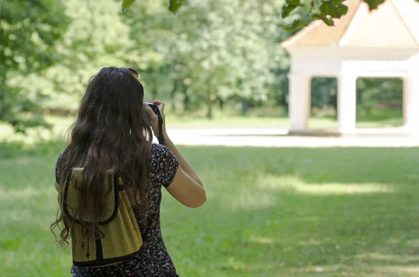 Widok z tyłu z młodą kobietę, fotografowanie, się w zabytkowym budynku w przyrodzie z niewyraźne tło — Zdjęcie stockowe