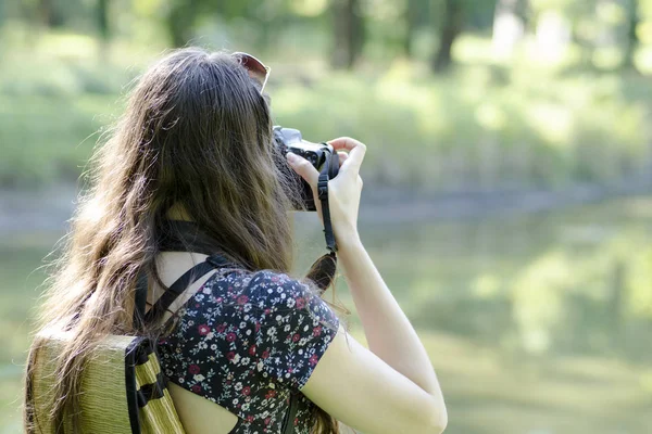 Vista trasera de una joven fotografiando la naturaleza con un fondo borroso —  Fotos de Stock